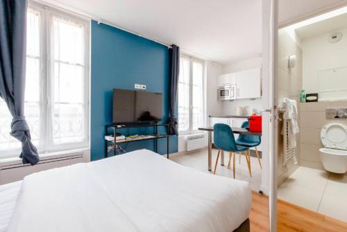 凡尔赛Le Studio Versaillais的卧室配有白色的床和蓝色的墙壁