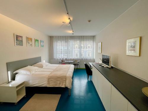 卢森堡多莫斯酒店的一间卧室配有一张床和一张书桌及电视