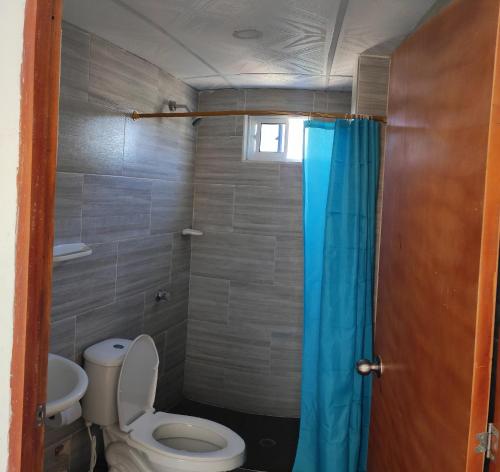 塔甘加Emvacamo'的浴室设有卫生间和蓝色的浴帘。