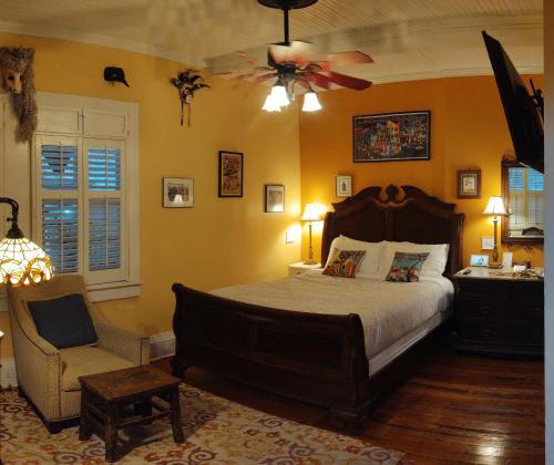 新奥尔良The Blue60 Marigny Inn的一间卧室配有一张床、一把椅子和吊扇