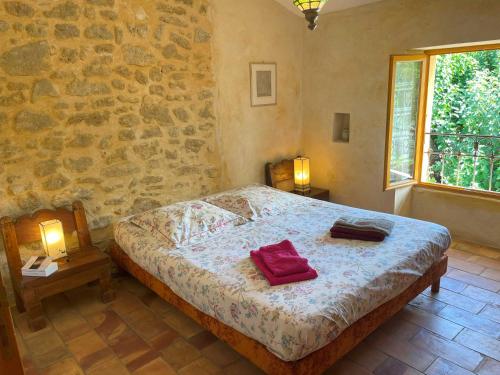 叙兹拉鲁斯Mas des Lavandes - 3 gîtes de charme au calme avec grande piscine en Drôme-Provençale的一间卧室设有一张床和石墙