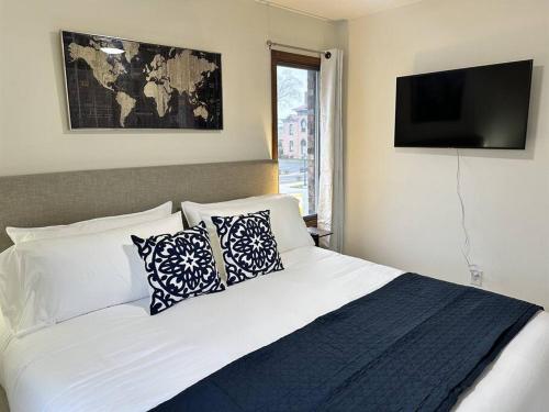 斯普林菲尔德Capital Suite on 6th Street - King Bed / Downtown!的卧室配有带枕头的白色床和电视。