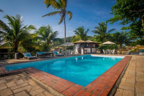 布希奥斯Pousada Lestada by Latitud Hoteles的一座拥有蓝色海水和棕榈树的游泳池