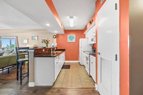 默特尔比奇Oceanfront Get Away的厨房设有橙色墙壁、白色橱柜和桌子