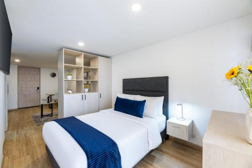 波哥大Torre Ventto Lofts的卧室配有一张蓝色色调的大型白色床。
