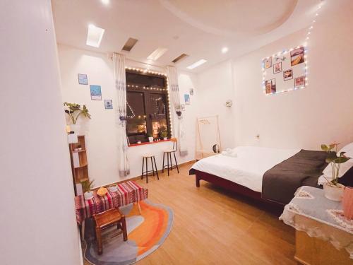 大叻House Thị Đà Lạt的一间卧室配有一张床、一张桌子和一个窗户。