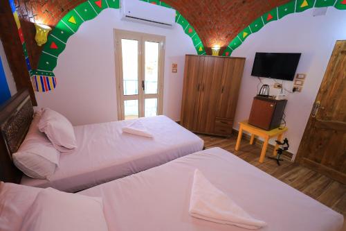 阿斯旺Nubian Popeye - Roof top - Nile View的一间卧室设有两张床和一个拱形天花板