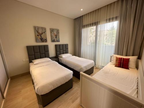 塞拉莱Hawana Salalah Villa的一间卧室设有两张床和窗户。