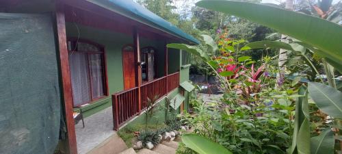 德雷克Corcovado & Drake Inn的绿色房子,设有种有鲜花和植物的阳台
