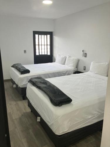 特基拉Hospedajes Nuñez Tequila的客房设有三张床、白色床单和窗户。