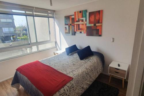 圣地亚哥Espectacular departamento Ñuñoa的一间卧室配有一张带蓝色枕头的床和一扇窗户。