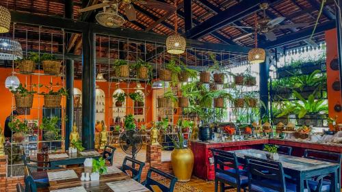 暹粒印度支那吴哥住宅酒店的一间设有桌椅和盆栽的餐厅