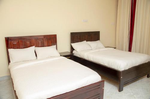 Eziana palm Hotels的配有衬衫的小客房内的两张床