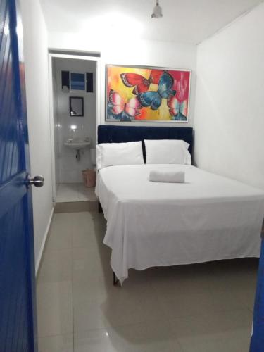 巴兰基亚HOSTAL BARRANQUILLA INN的卧室配有白色的床和墙上的绘画作品