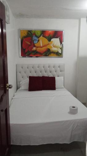 巴兰基亚HOSTAL BARRANQUILLA INN的卧室配有一张白色床,墙上挂有绘画作品