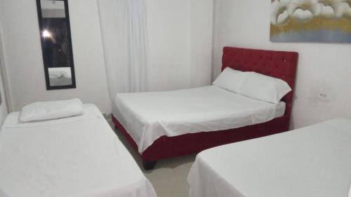 巴兰基亚HOSTAL BARRANQUILLA INN的一间设有两张床和红色椅子的房间