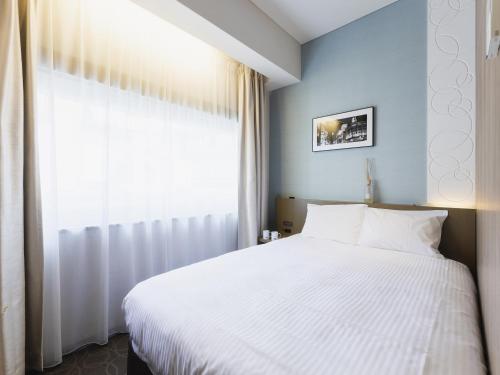 东京格拉斯丽银座酒店的卧室配有白色的床和窗户。