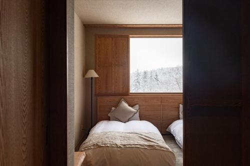 东川町旭岳汤元羽日式旅馆的一间小卧室,配有床和窗户