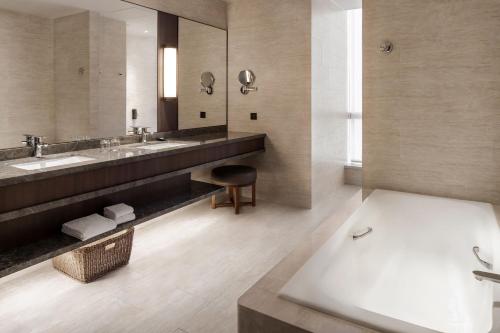 台北台北六福万怡酒店的浴室配有两个盥洗盆和浴缸。