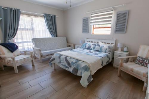 杰弗里湾Surf n Sea Beachfront Holiday Home的一间卧室配有一张床、一把椅子和窗户。