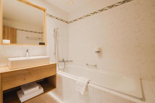 高塔特拉山Rodinný Hotel Hubert High Tatras的浴室配有盥洗盆、浴缸和盥洗盆