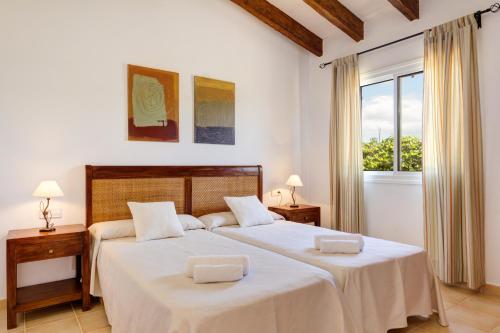 苏昂博Villas Menorca Sur的一间卧室设有两张带白色床单的床和窗户。
