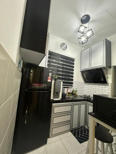 亚娄MK Homestay Perlis的厨房配有黑白橱柜和黑冰箱。
