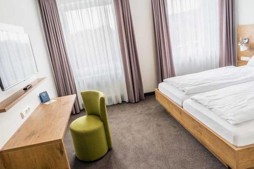 比登科普夫Lahn Hotel的一间卧室配有一张床、一张桌子和一把椅子