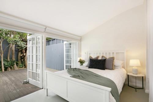 悉尼Paddington Garden Cottage with fast Wifi的一间白色卧室,配有床和庭院