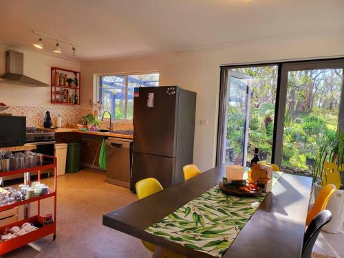 美德罗巴斯The Yellow Koala - Vibrant Home in Medlow Bath的厨房配有桌子和冰箱。