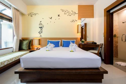 普吉镇A2 Pool Resort - SHA Plus的卧室配有带蓝色枕头的大型白色床