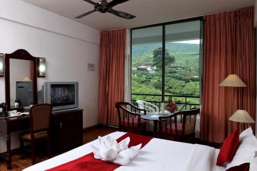 蒙纳Hotel C7 Munnar的配有一张床、一张书桌和一扇窗户的酒店客房