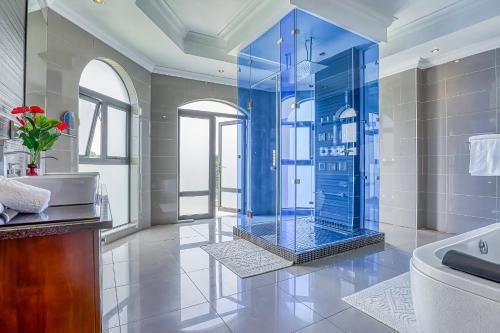 约翰内斯堡Villa Tasha Luxury Suites, Lanseria的浴室配有蓝色淋浴和浴缸