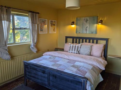 切尔滕纳姆Stylish 3 bed Cotswold cottage with stunning views的卧室配有一张带粉红色枕头的大床