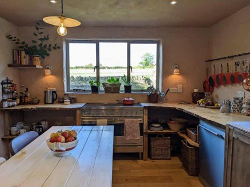 切尔滕纳姆Stylish 3 bed Cotswold cottage with stunning views的厨房里配有一张桌子,上面放着一碗苹果