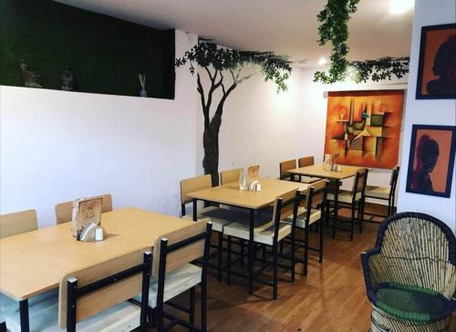 乌代浦Hostel Nirvana的一间设有桌椅的餐厅,墙上有一棵树