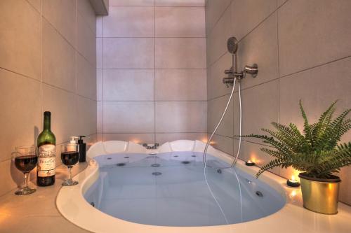 萨法德סוויטת גן עדן - Gan Eden Suite的浴缸,包括一瓶葡萄酒和植物