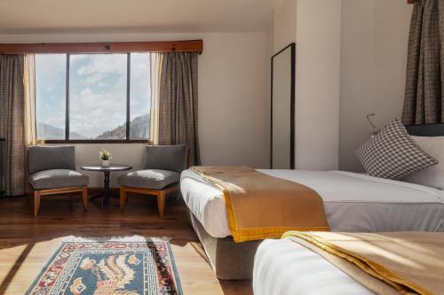 廷布Hotel Dralha的酒店客房带两张床和一张桌子以及椅子。