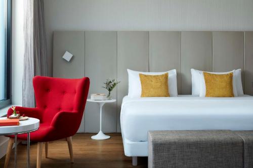 美因河畔法兰克福Avani Frankfurt City Hotel - previously NH Collection Frankfurt City的酒店客房,配有一张床和一张红色椅子