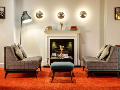 特尔福德Mercure Telford Centre Hotel的客厅配有两把椅子和壁炉