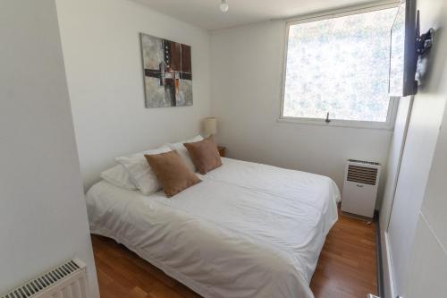 圣地亚哥Kennedy Apartments Los Militares的一个小房间,设有一张白色的床,配有窗户