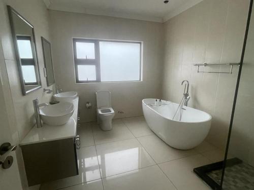 哈博罗内Villa54的带浴缸、盥洗盆和卫生间的浴室