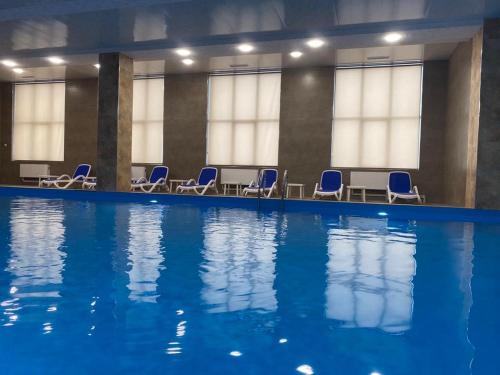 萨克德佐尔镇Uparthotel的大楼内带蓝色椅子的游泳池