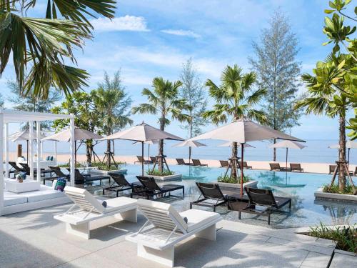 蔻立Pullman Khao Lak Resort的一个带椅子和遮阳伞的游泳池和海滩