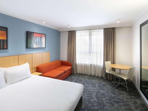 布里斯班Mercure Brisbane Garden City的酒店客房配有床、沙发和桌子。