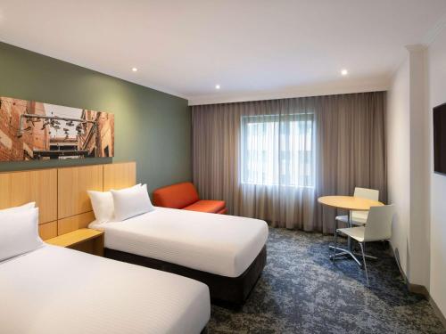 墨尔本Mercure Melbourne Southbank的酒店客房设有两张床和一张桌子。