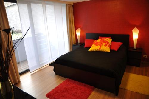 布鲁塞尔福利特之家公寓的一间卧室配有黑色床和红色和黄色枕头