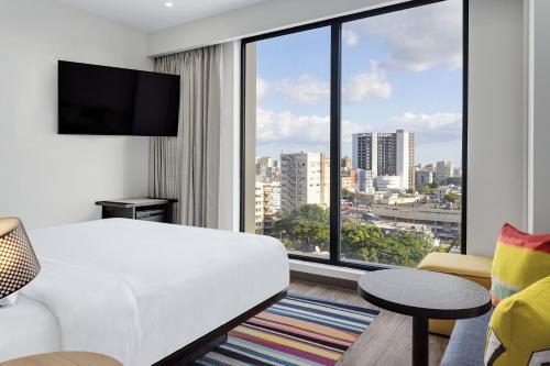 圣多明各Aloft Santo Domingo Piantini的酒店客房设有白色的床和大窗户。