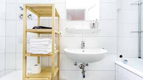 弗莱堡Apartments an der Uniklinik的浴室设有白色水槽和带毛巾的架子。