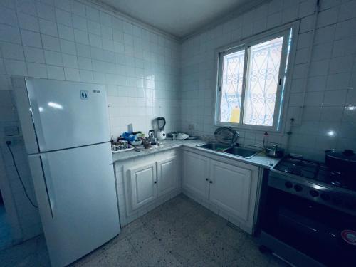拉马萨Villa le bon coin de la marsa的厨房配有冰箱、水槽和窗户。
